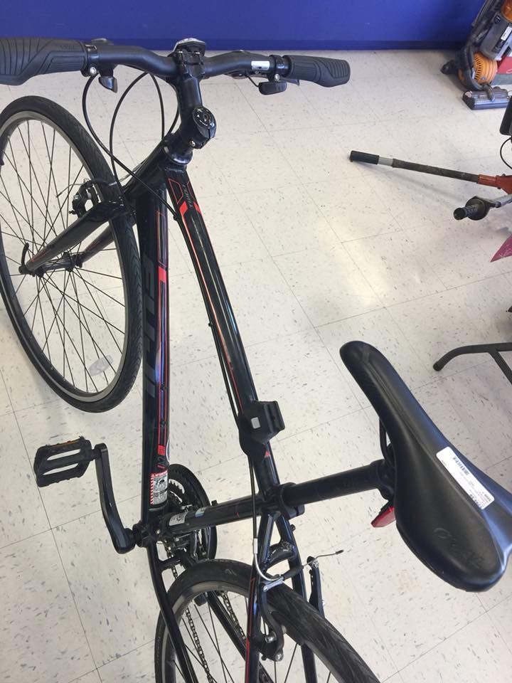 Black and red hybrid bicycle on a white and blue floor, viewed from above.