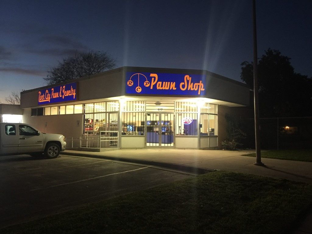 Three laptops on a table: pink, purple, and silver, each with a price tag displayed.