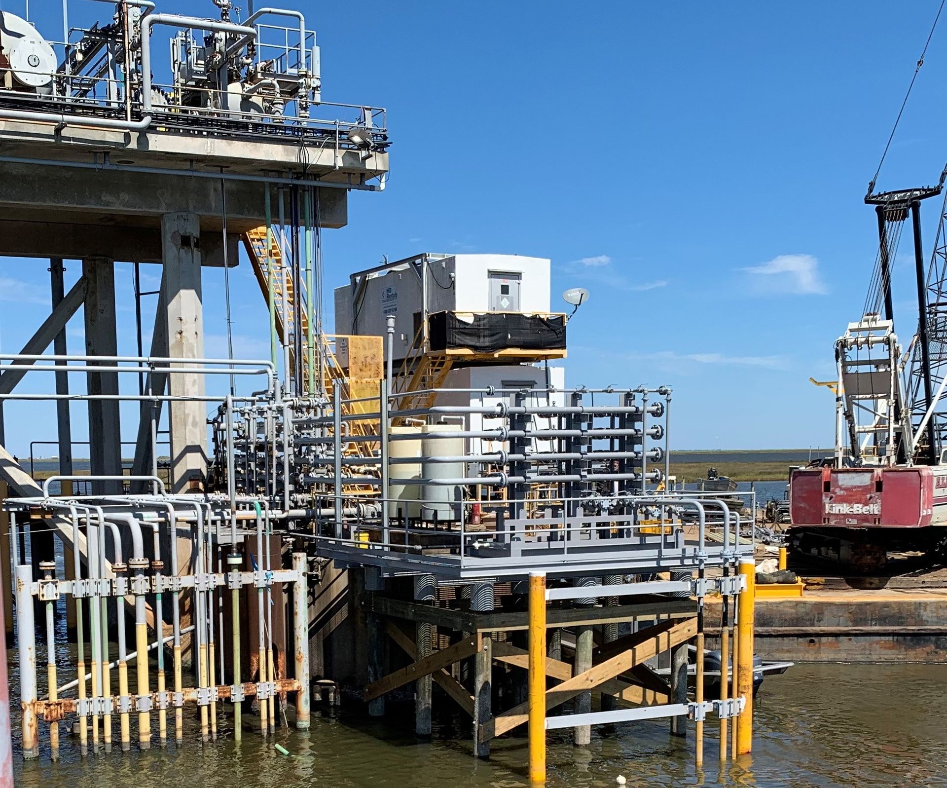 A large red crane is sitting on top of a dock next to a body of water.