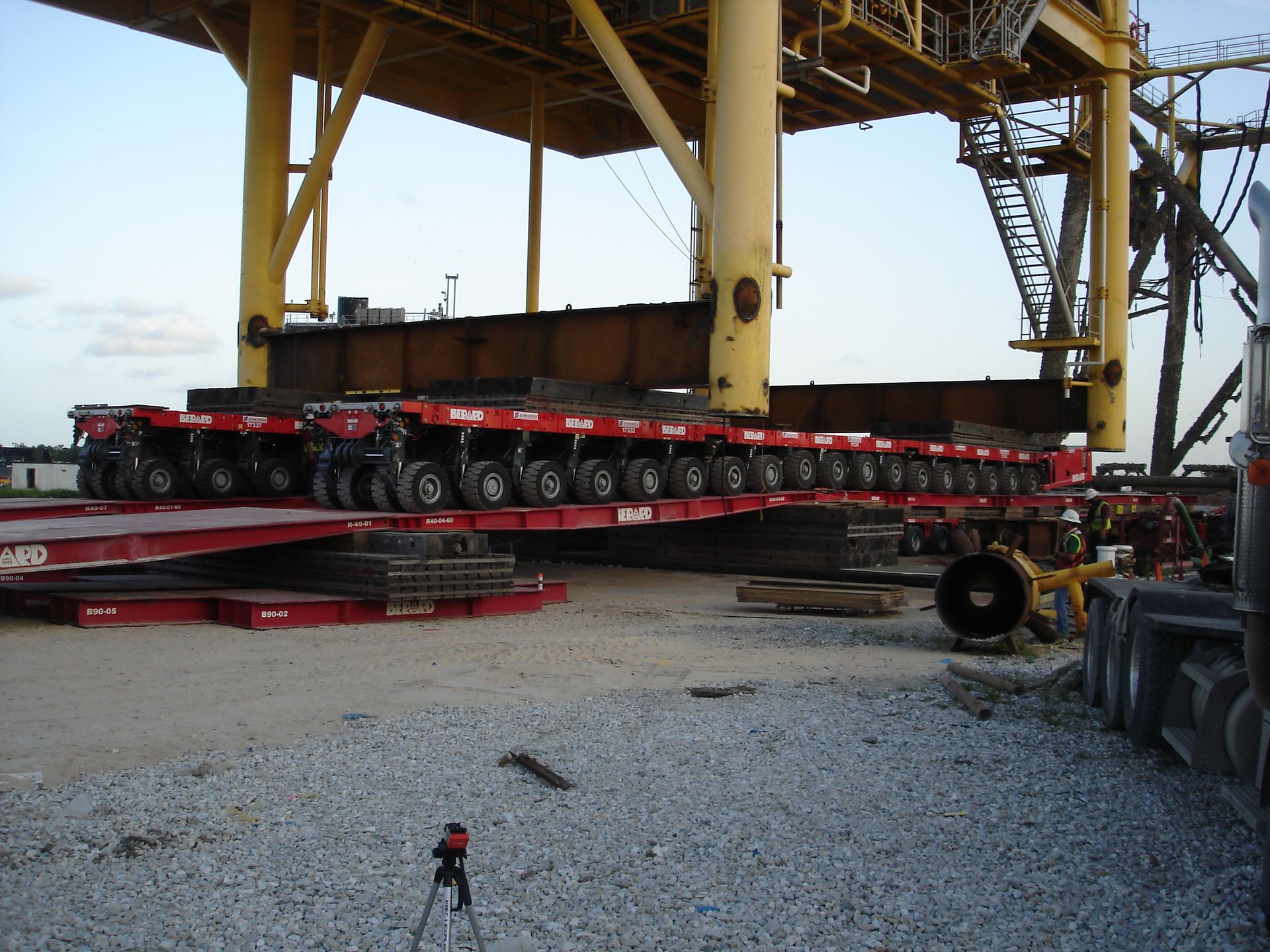 A crane is being loaded with a very long trailer that says ' heavy duty ' on it