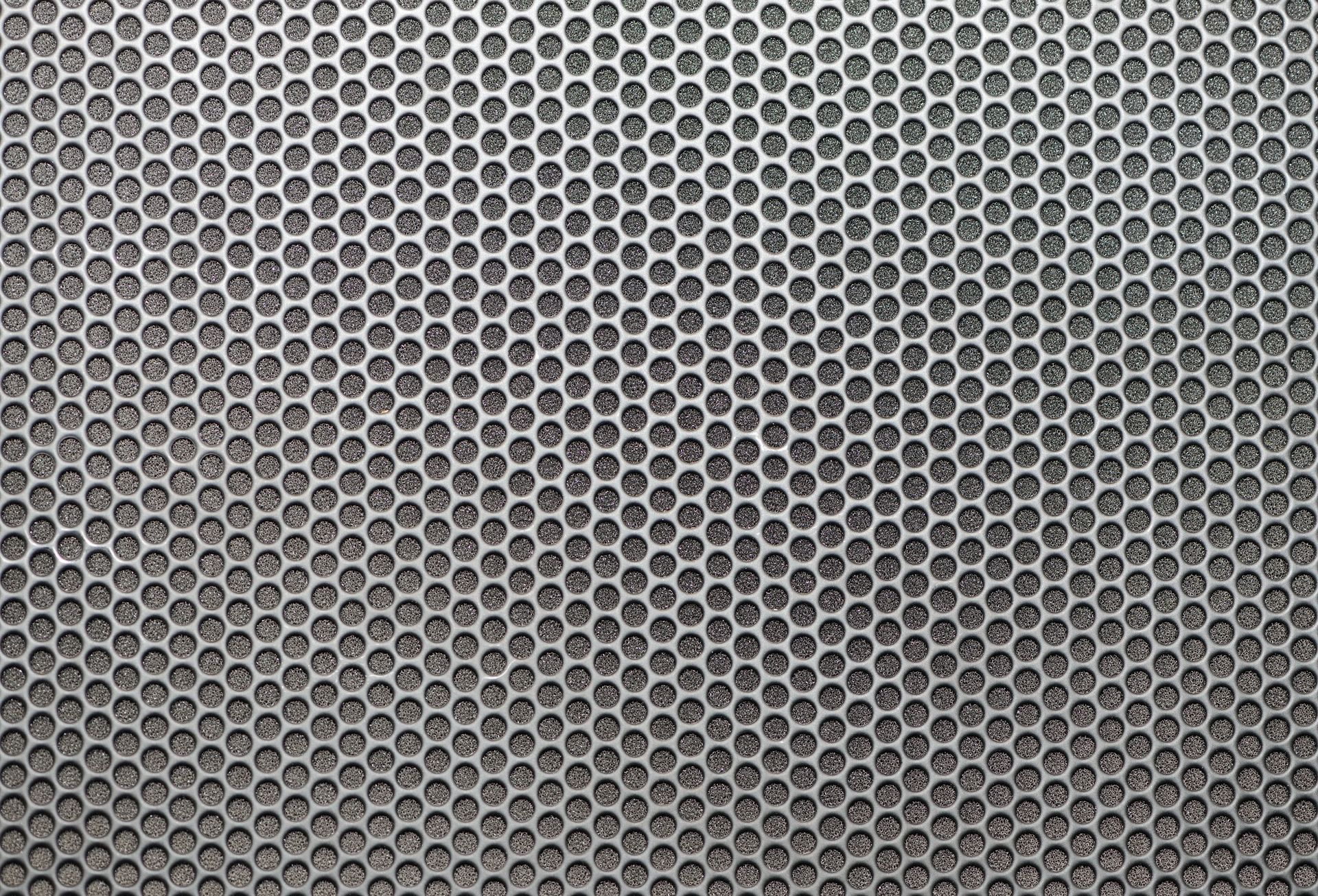 Gray perforated metal mesh pattern with evenly spaced hexagonal holes