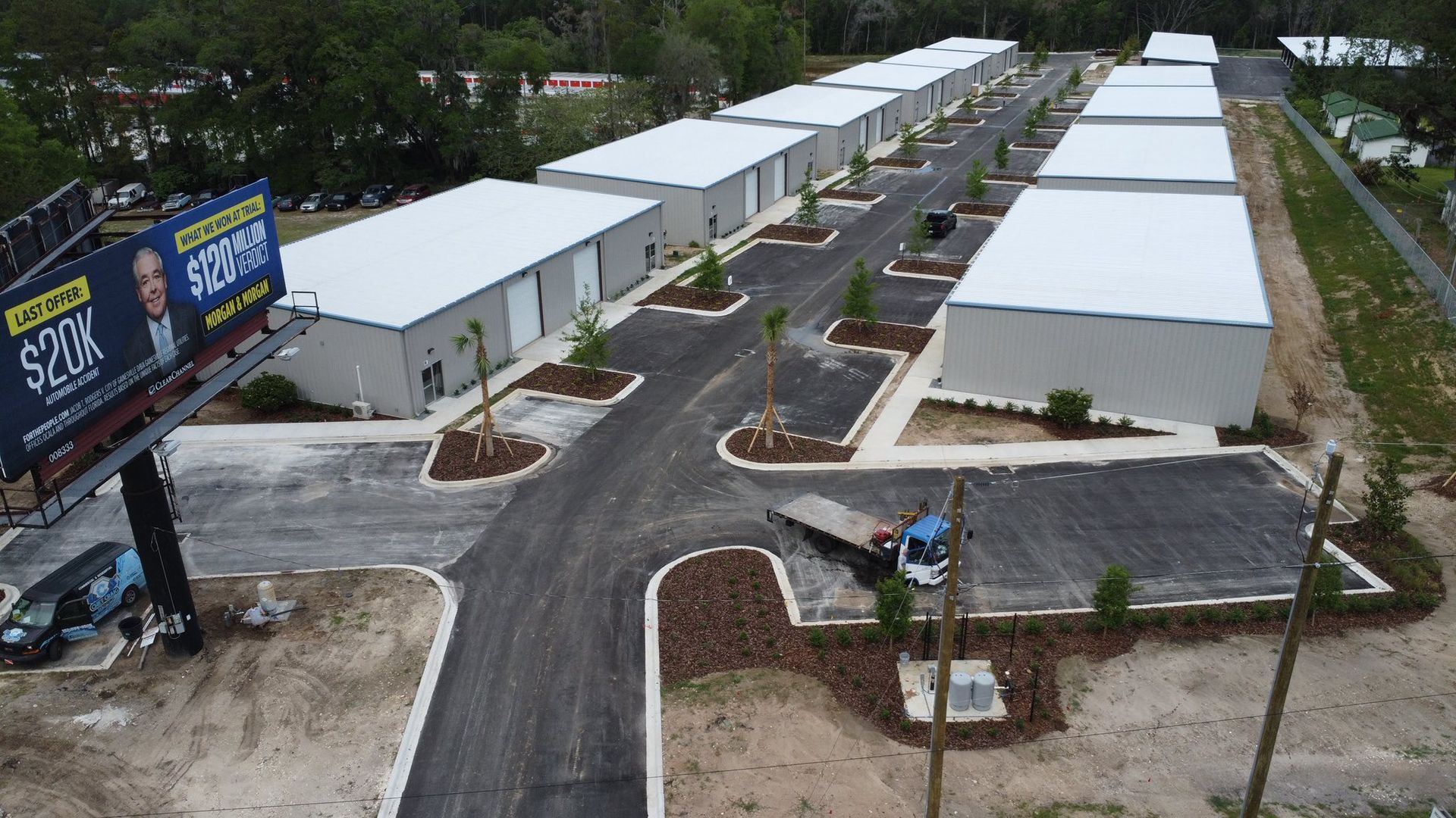 Aerial view of rows of white modular buildings along curved paved roads and landscaped lots