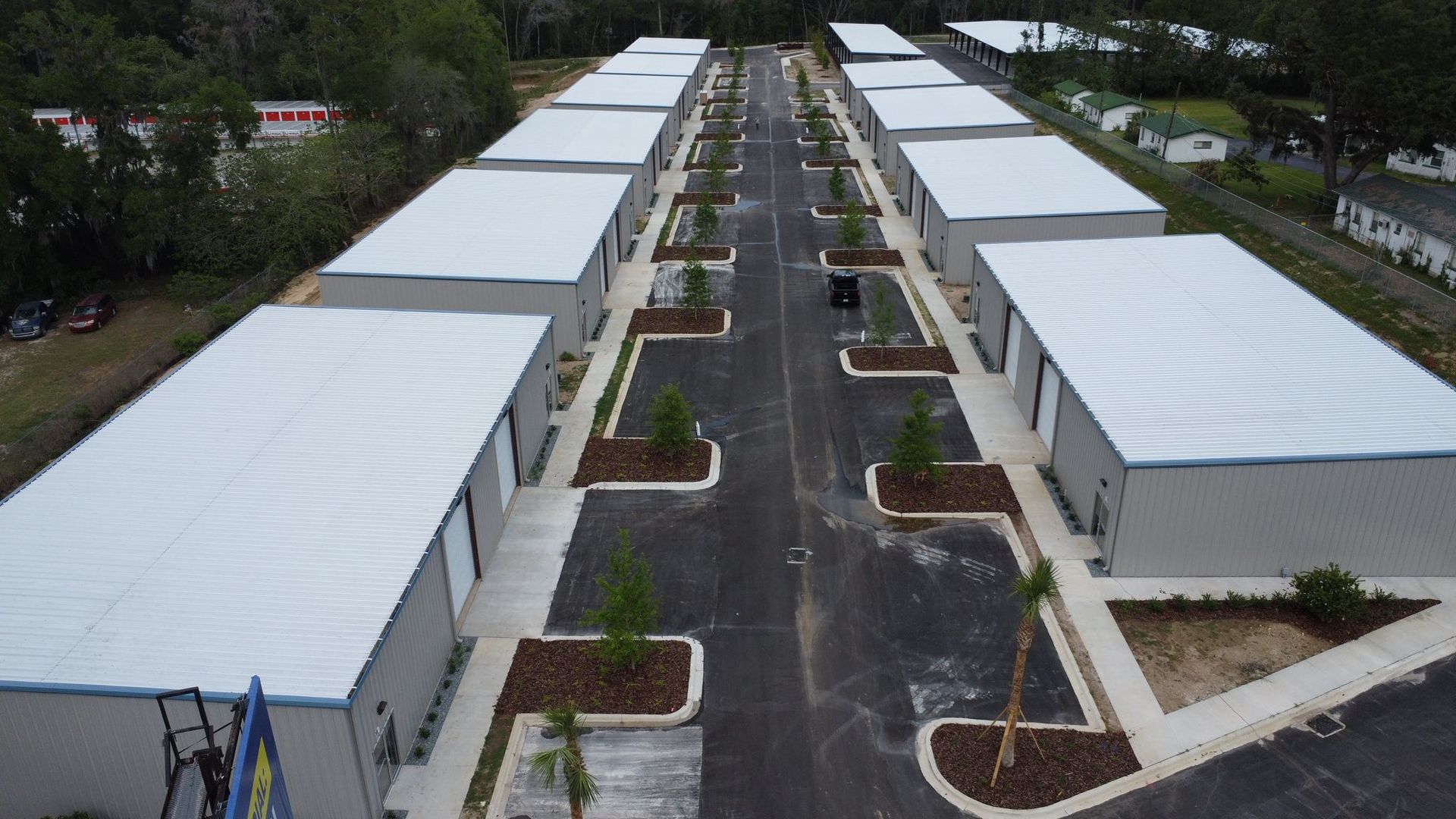 Aerial view of rows of white-roofed modular buildings along paved paths in a camp-like layout