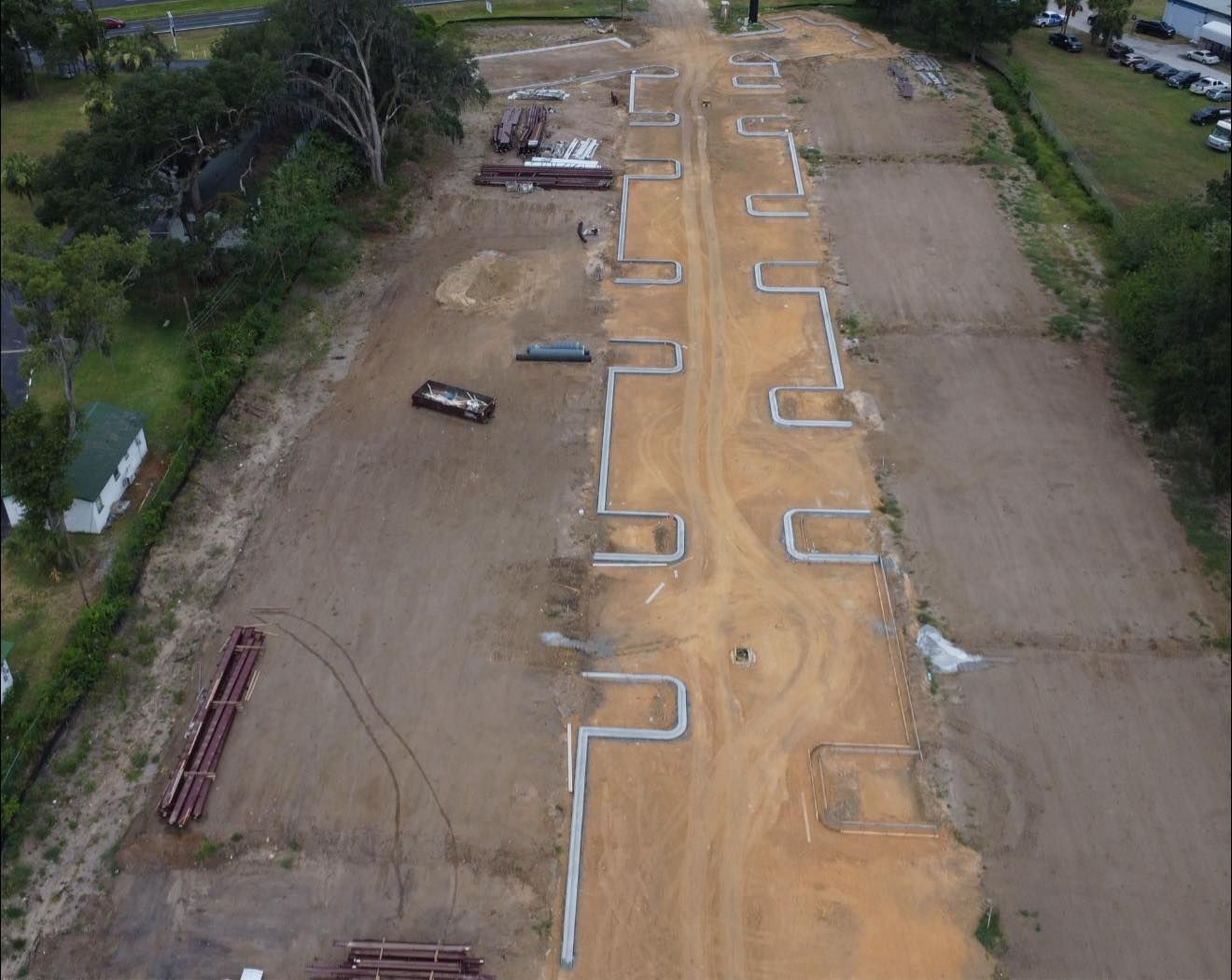 Aerial view of a construction site with a long dirt path and evenly spaced concrete forms.