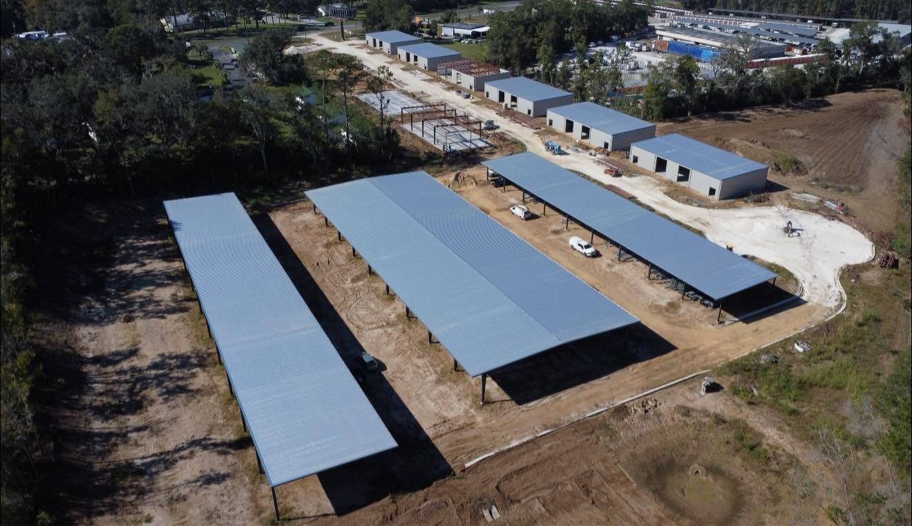 Aerial view of several long metal-roofed buildings in a rural industrial yard.