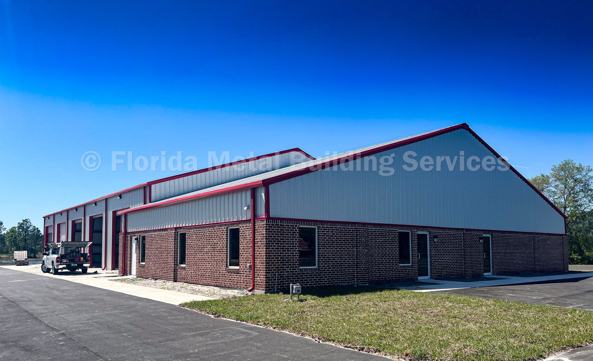 Single-story red brick commercial building with white roof and blue sky