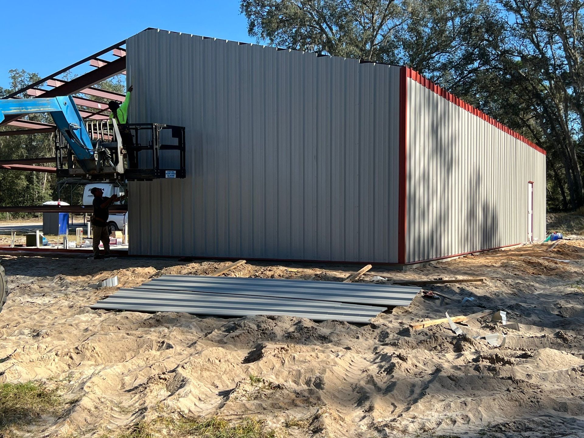 Small gray metal building with red trim on a dirt lot, seen from the side
