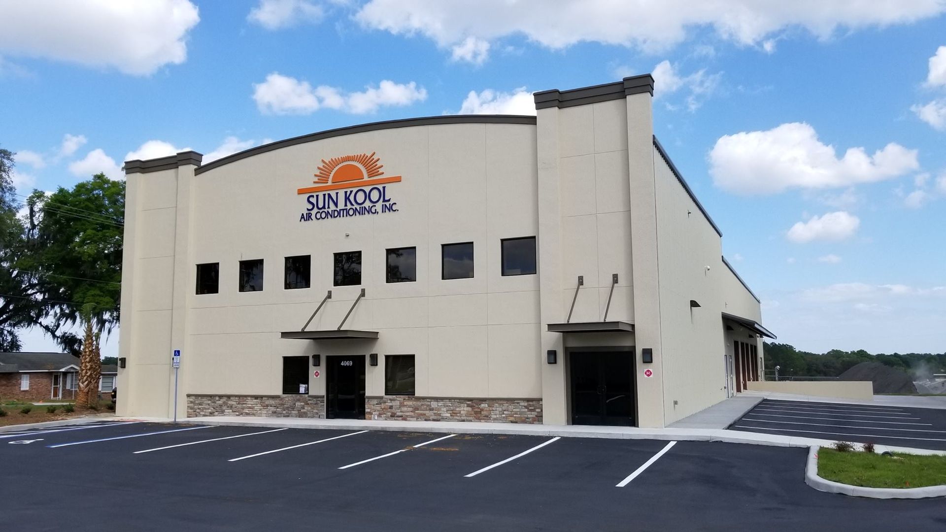 Front view of a tan commercial building with a parking lot and blue sky