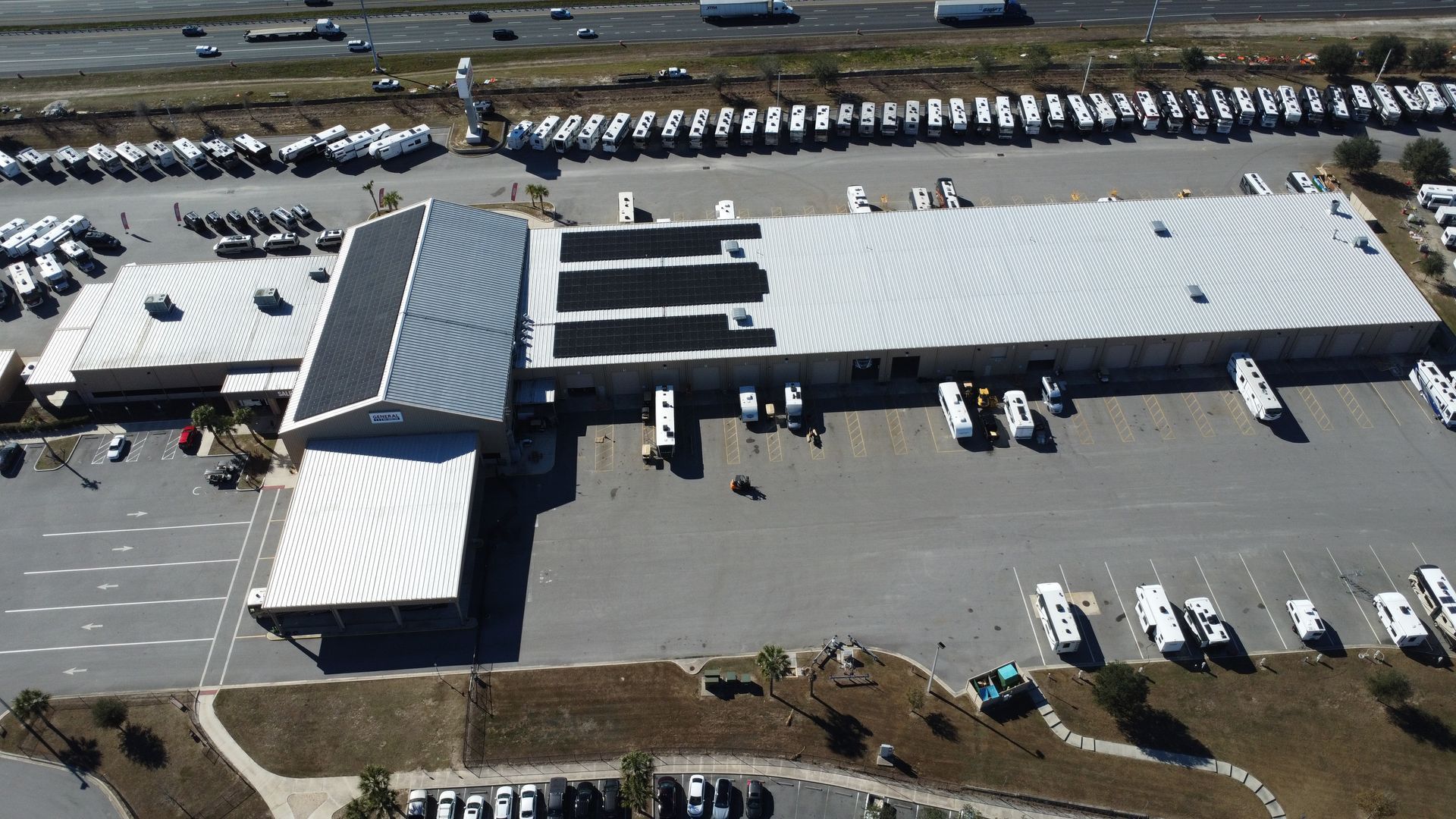 Aerial view of a large commercial building surrounded by a parking lot filled with numerous recreational vehicles.