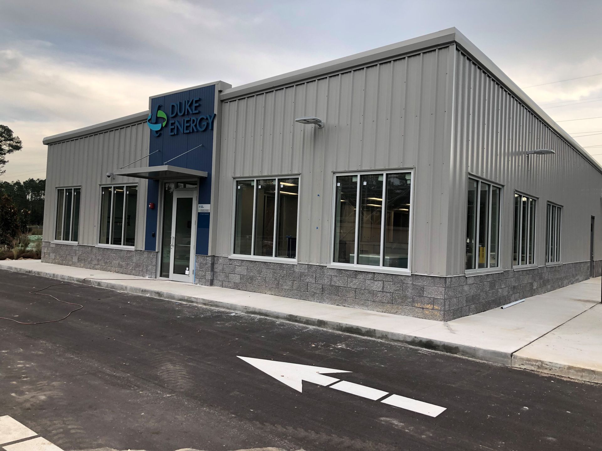 A modern, single-story light gray metal building with a blue sign reading 