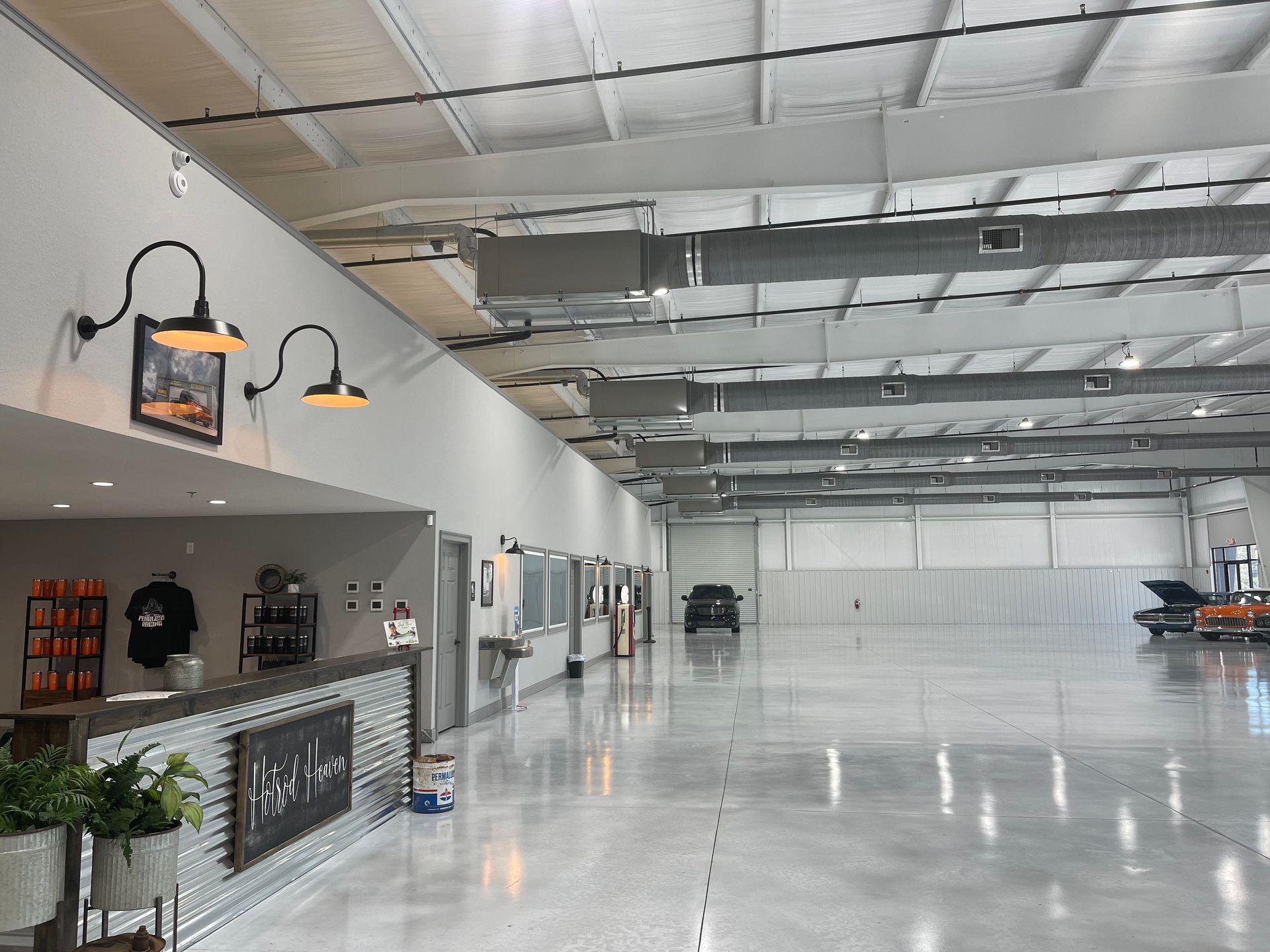 A wide view of a spacious warehouse interior with a reception desk in the foreground and a large vehicle in the distance.