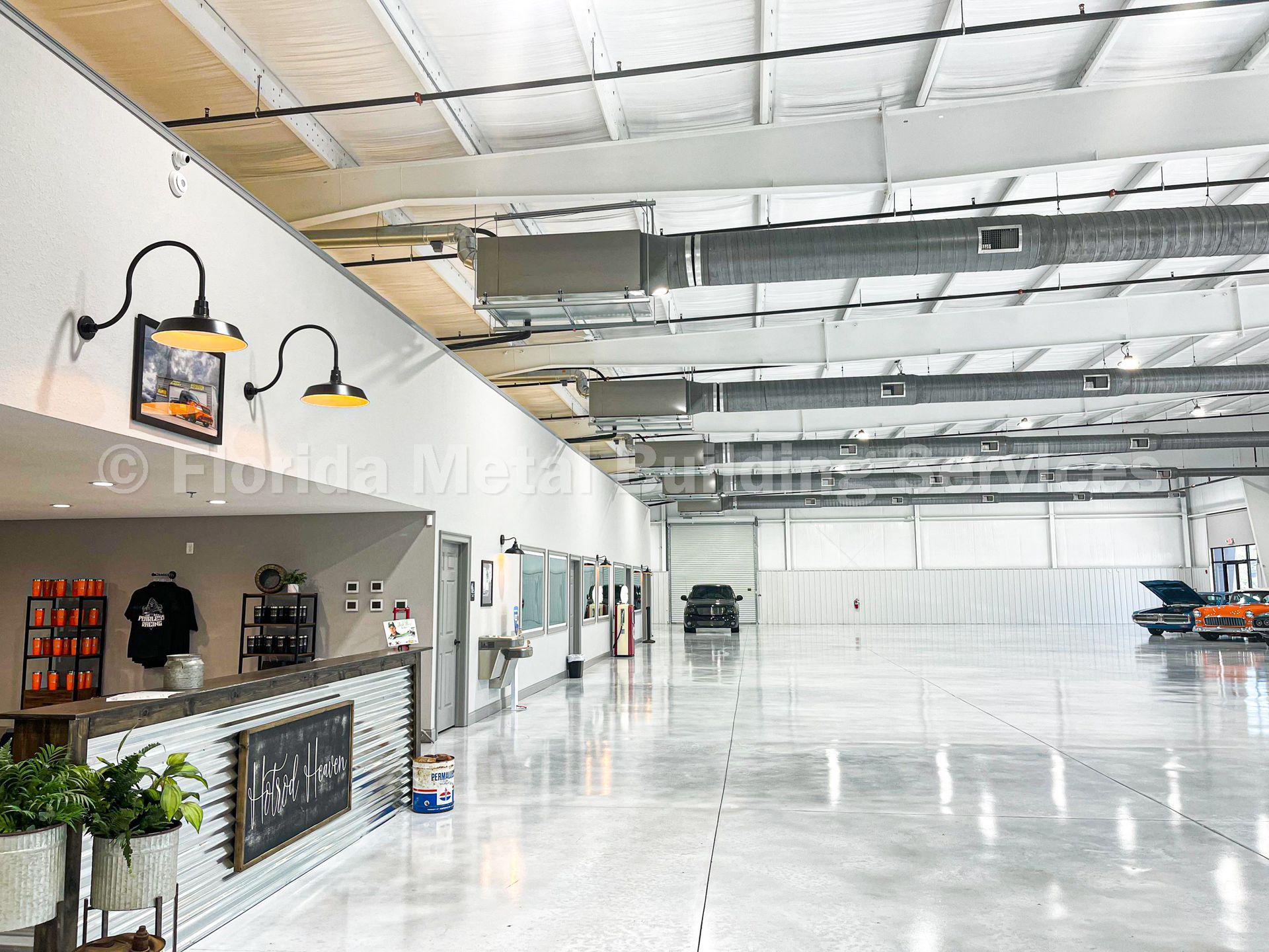 A modern warehouse office space with a reception desk, polished concrete floors, and a large, open industrial shop area.
