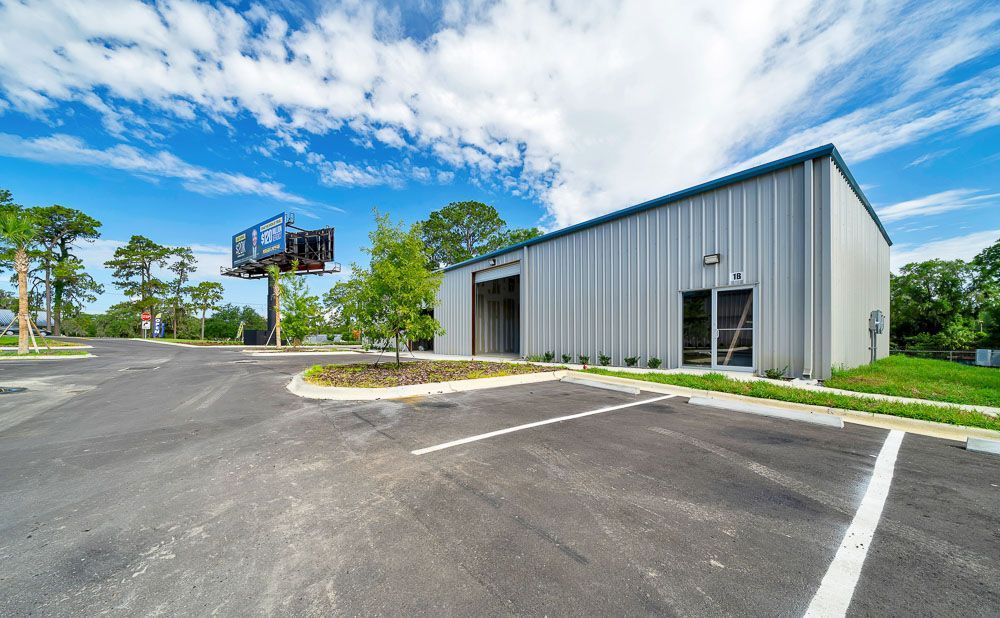 Modern gray industrial building beside an empty paved lot under a blue sky