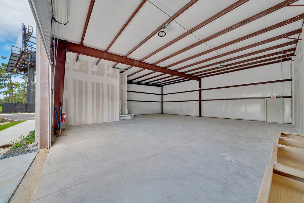 Empty industrial warehouse interior with concrete floor, white walls, and exposed red steel beams