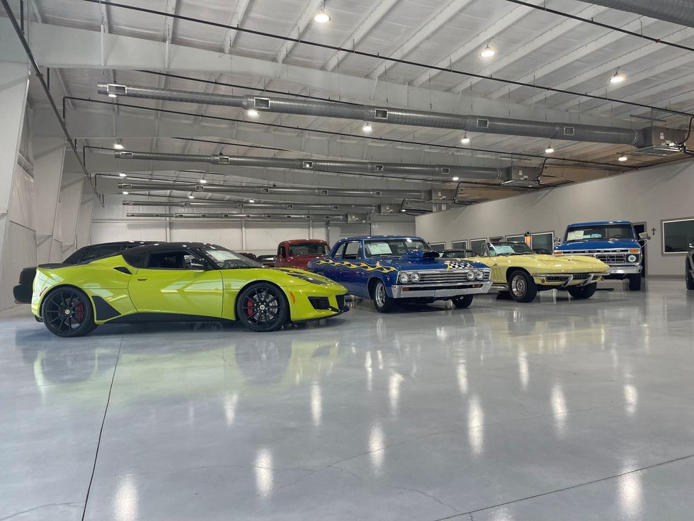 A lime green sports car parked in a spacious, brightly lit showroom with several other classic and vintage vehicles.