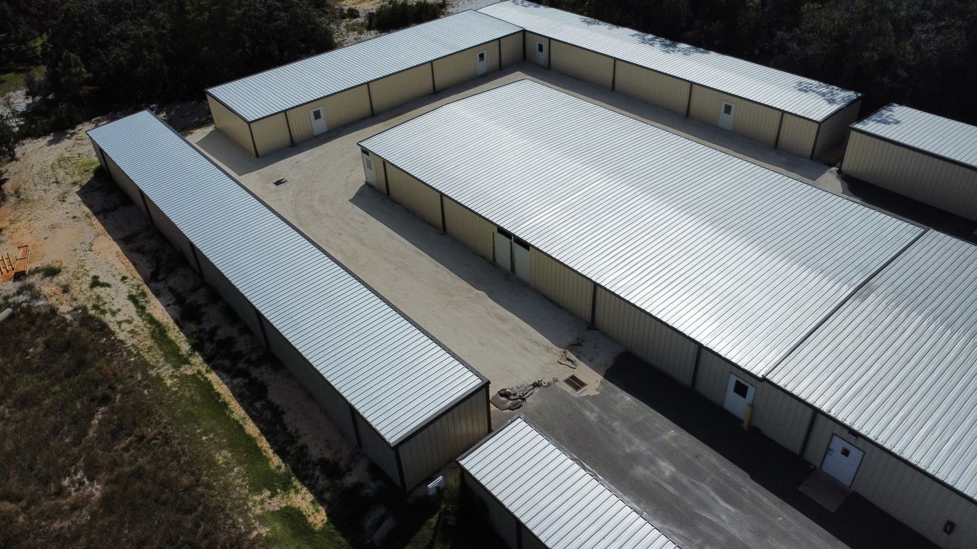 Aerial view of a U-shaped industrial building with light metal roofs and a central courtyard.
