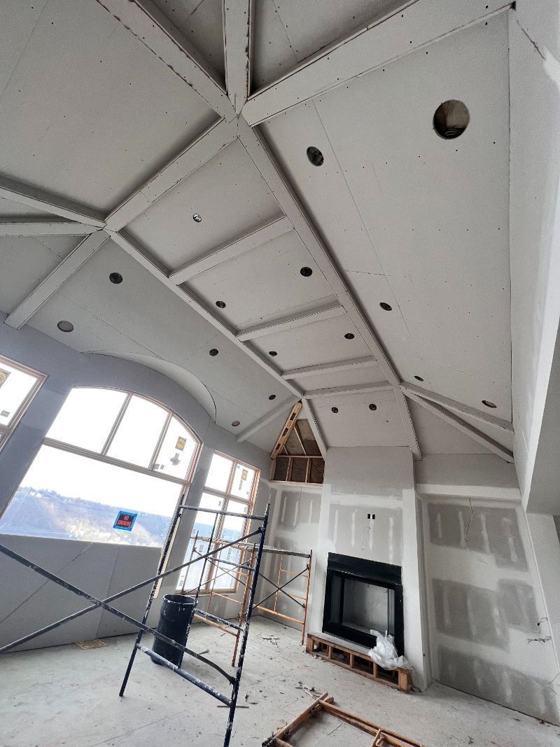 Interior view of a room under construction with a coffered ceiling, fireplace, and scaffolding.