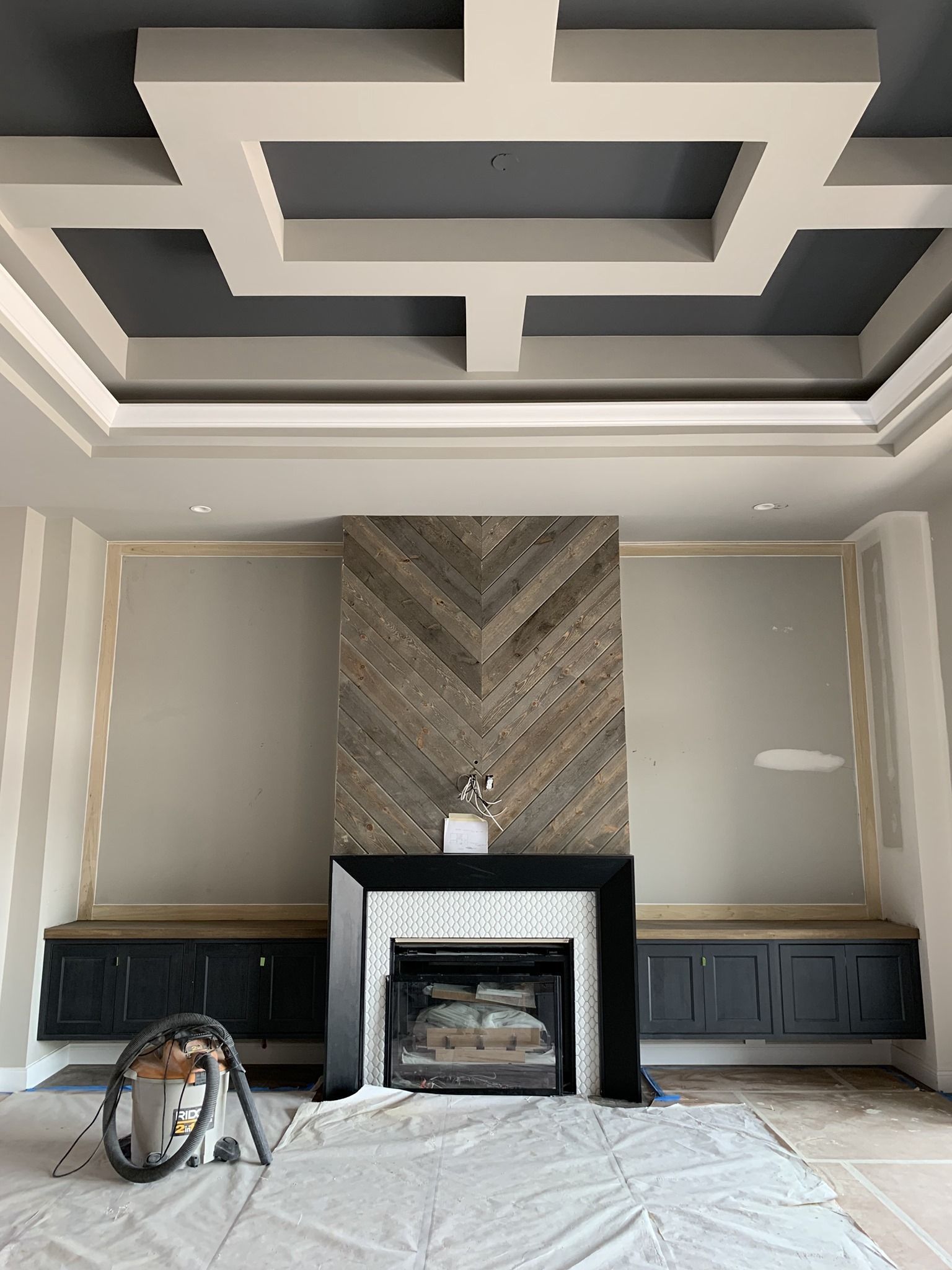 Living room with a wood-planked fireplace, black hearth, and built-in benches. Grey ceiling with white trim.