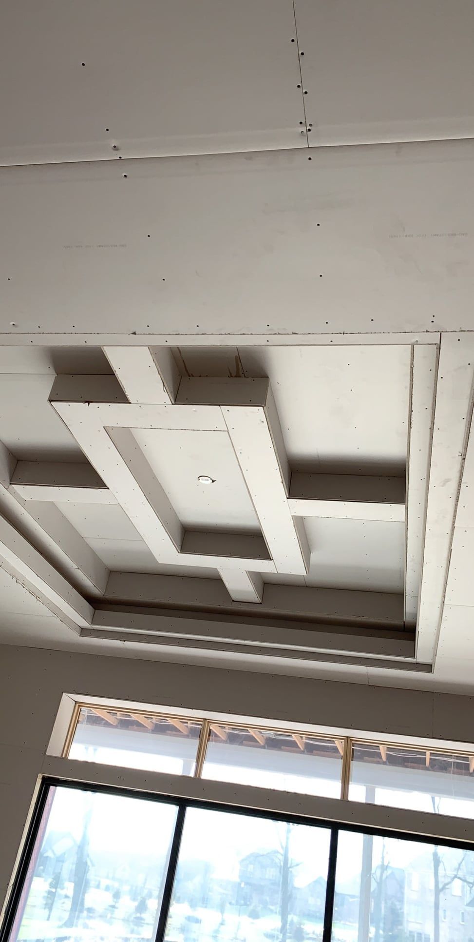 Ceiling with geometric recessed design; a window is visible in the foreground.