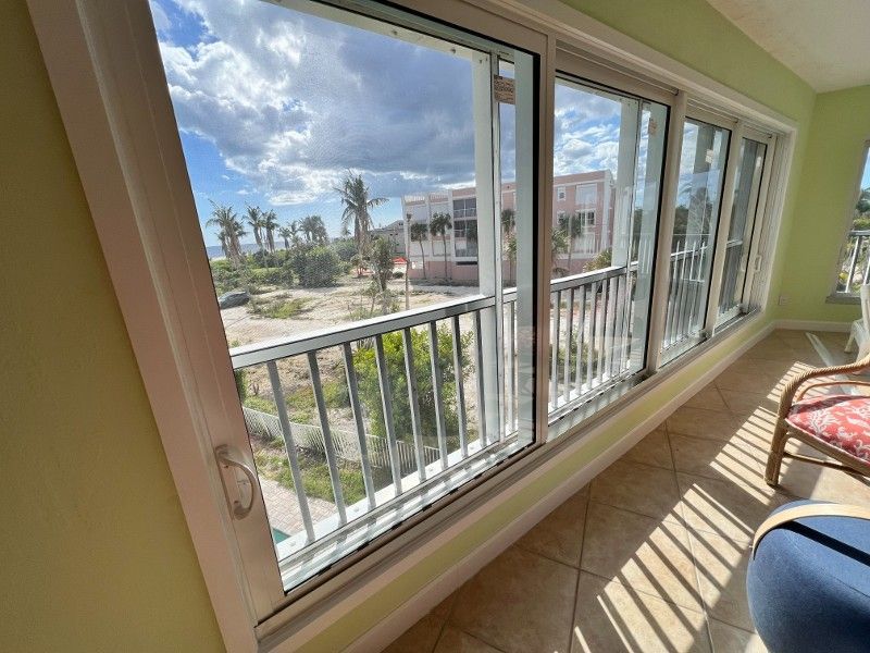 Balcony with a view: sliding glass doors, metal railing, outside scene of buildings and greenery.
