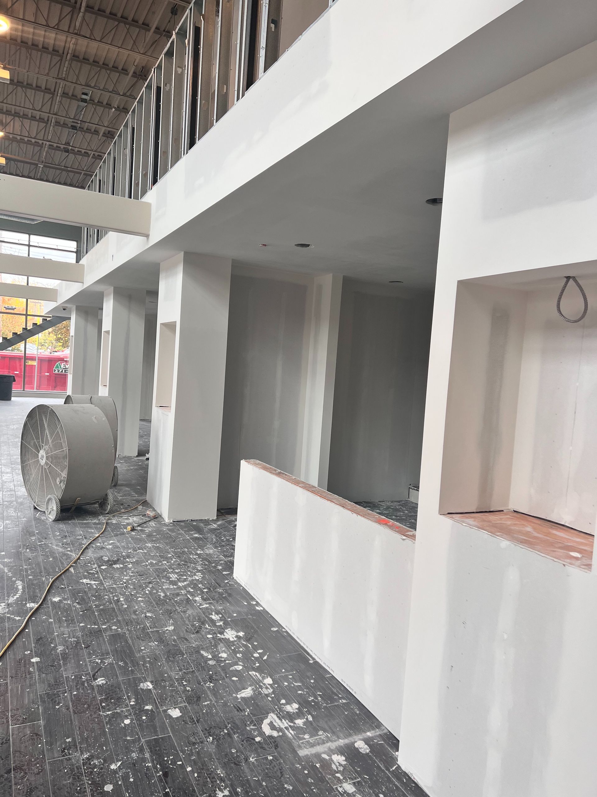 Interior construction: drywall walls and columns in a building. Unfinished floor and a roll of material.