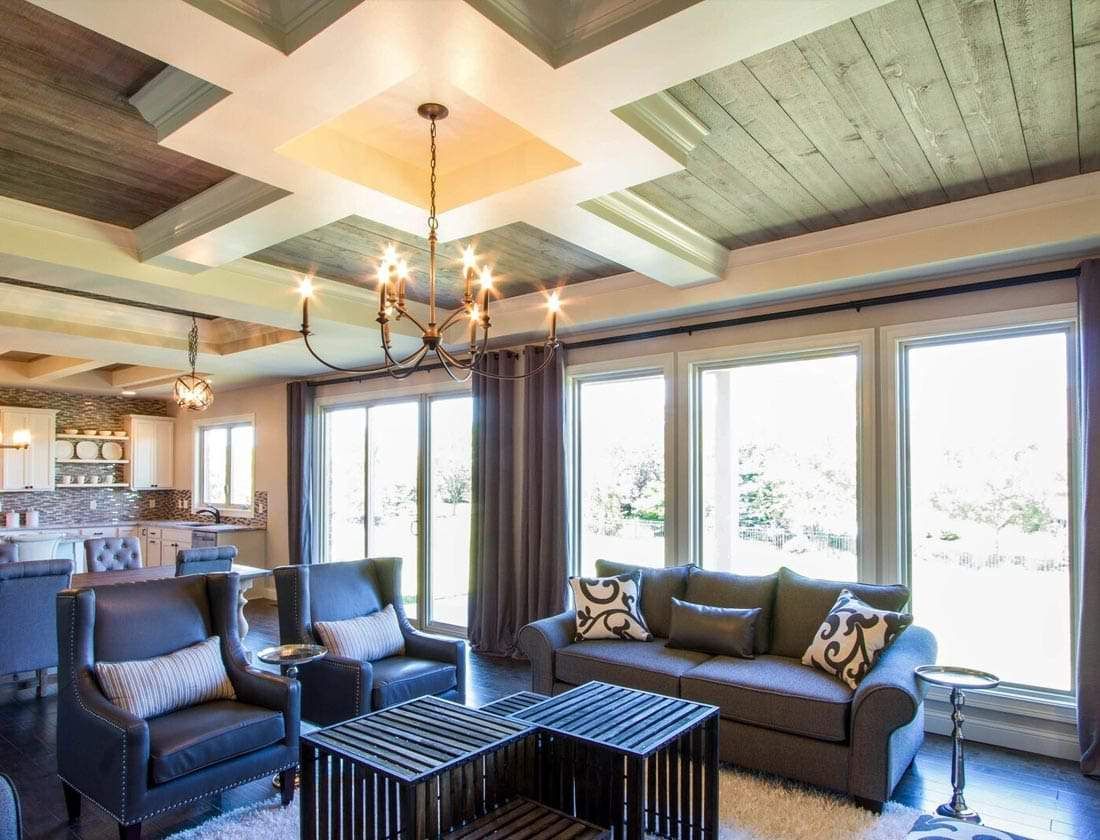 Living room with gray sofa, leather chairs, large windows, and decorative ceiling.