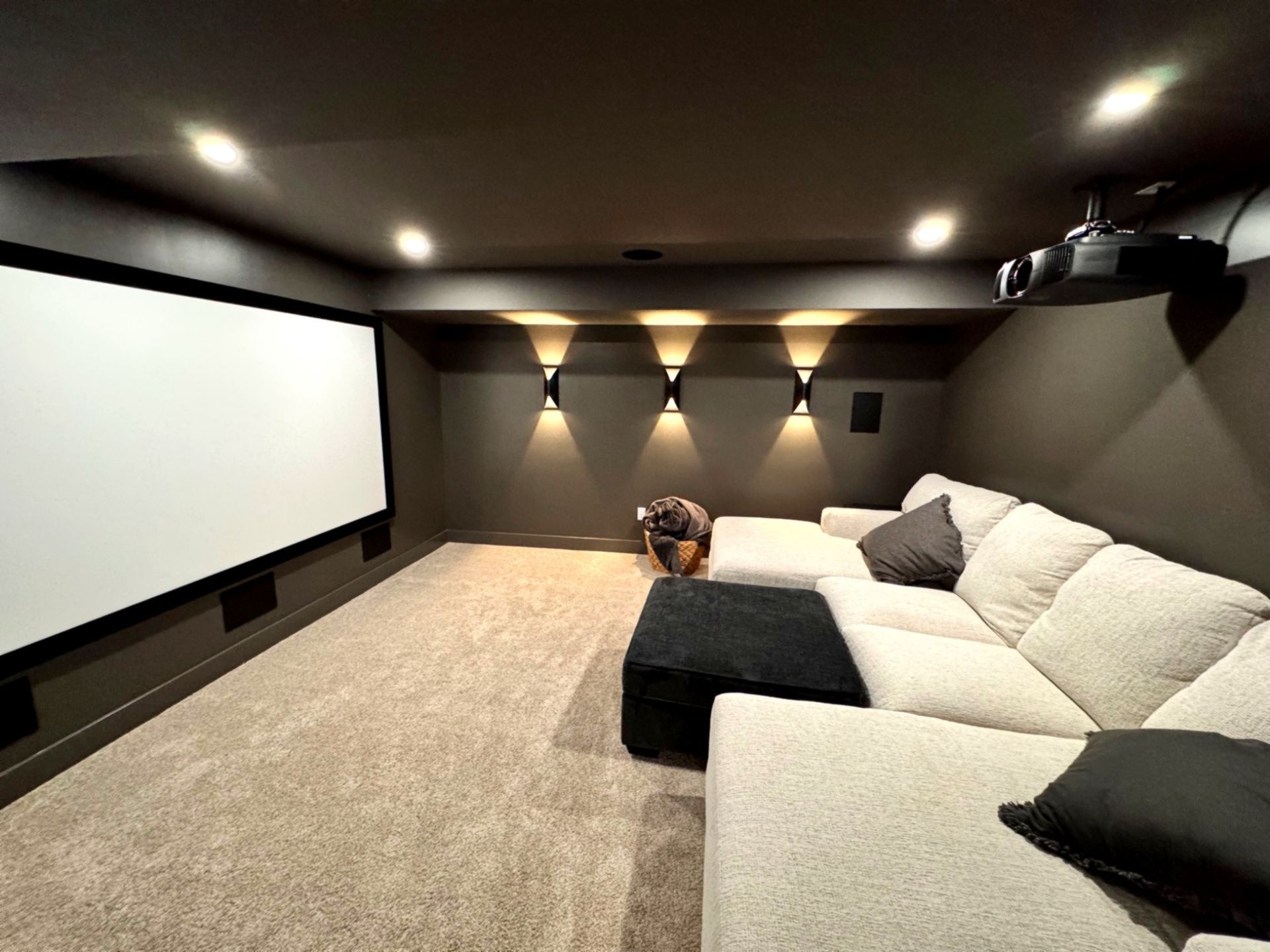 Cozy home theater with a large screen, plush sectional, and dim lighting.