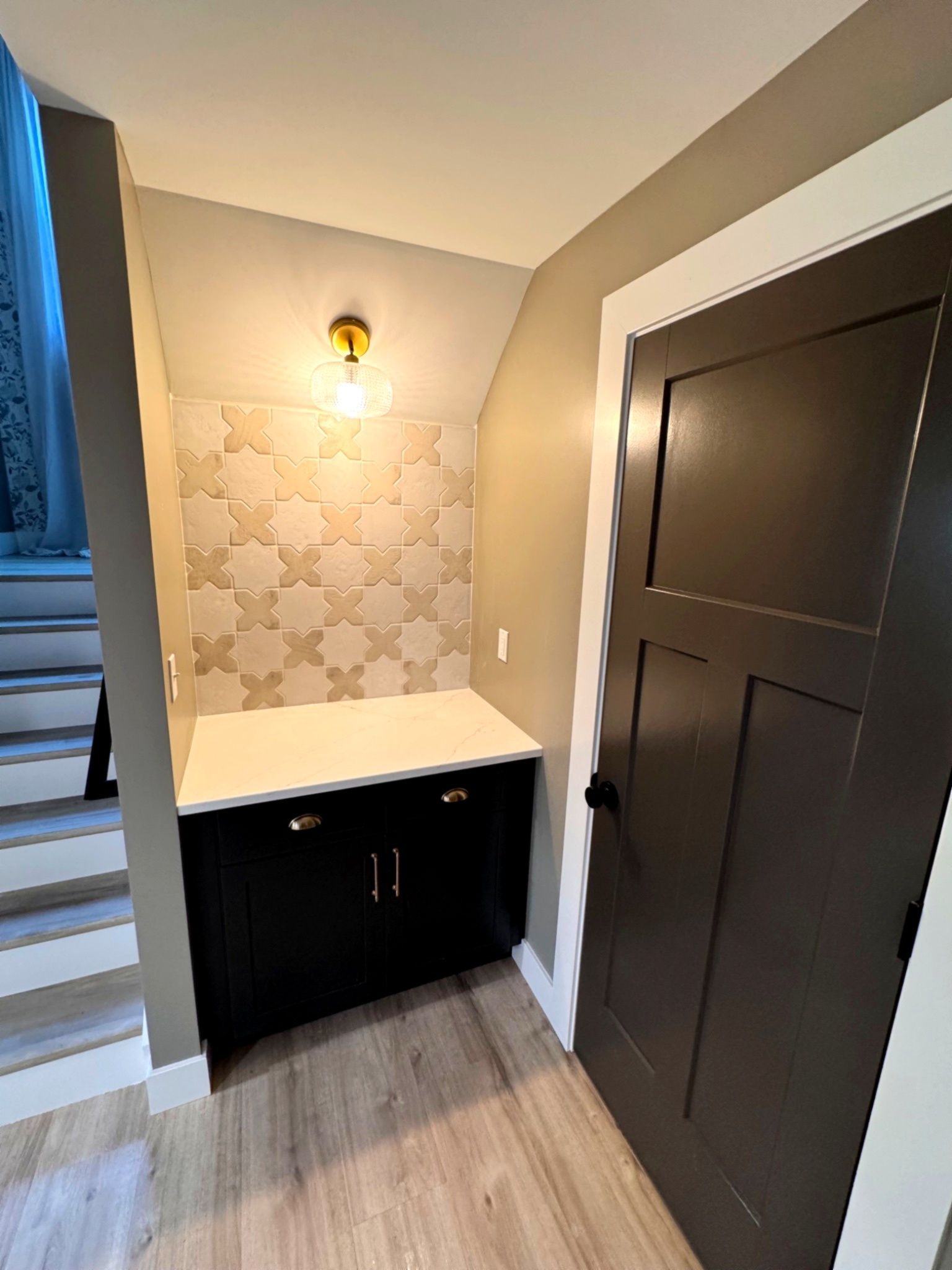 Black cabinet with white countertop and patterned tile backsplash in a small alcove.