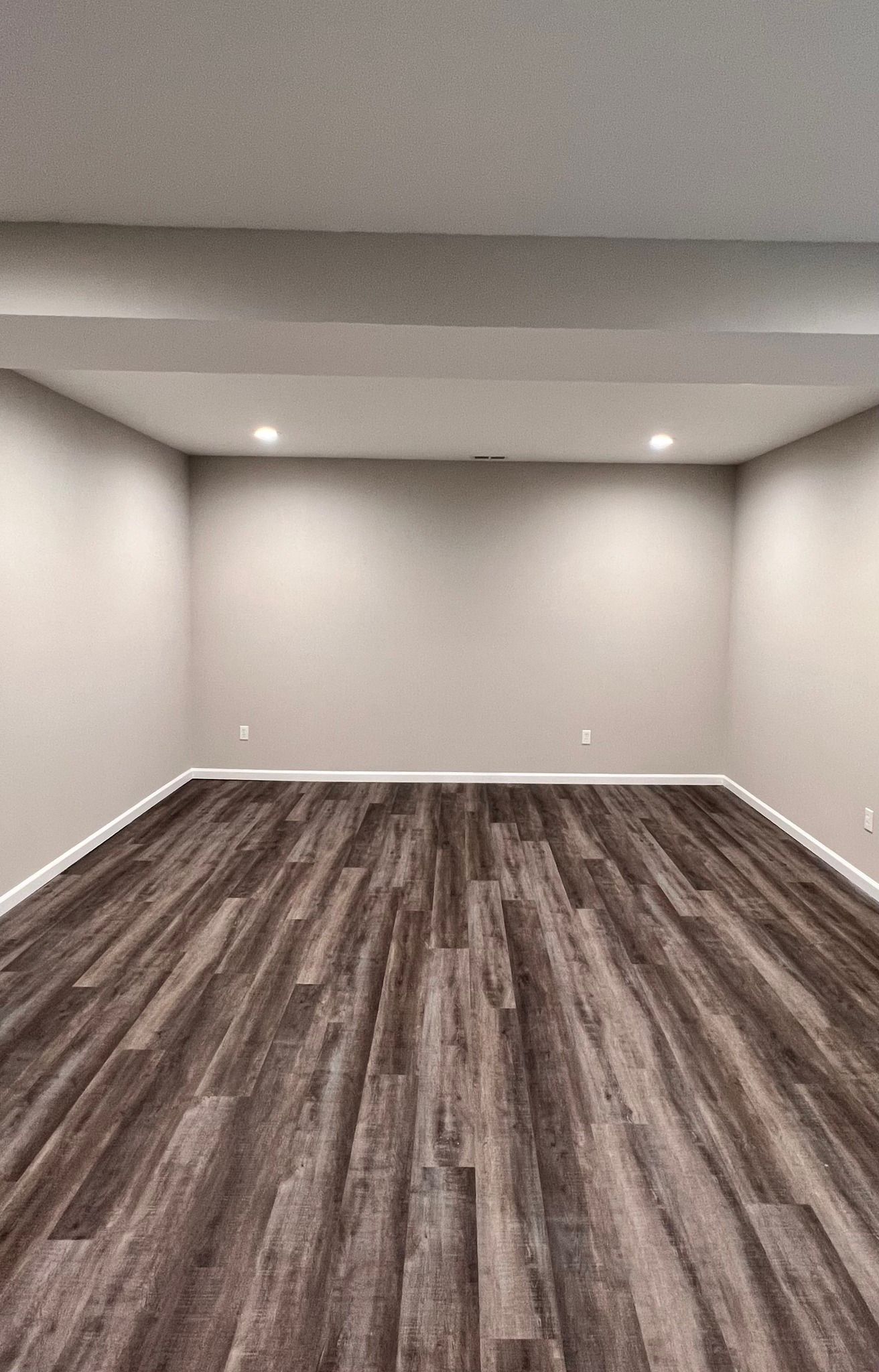 Empty room with wood-look floor, neutral walls, and recessed lighting.