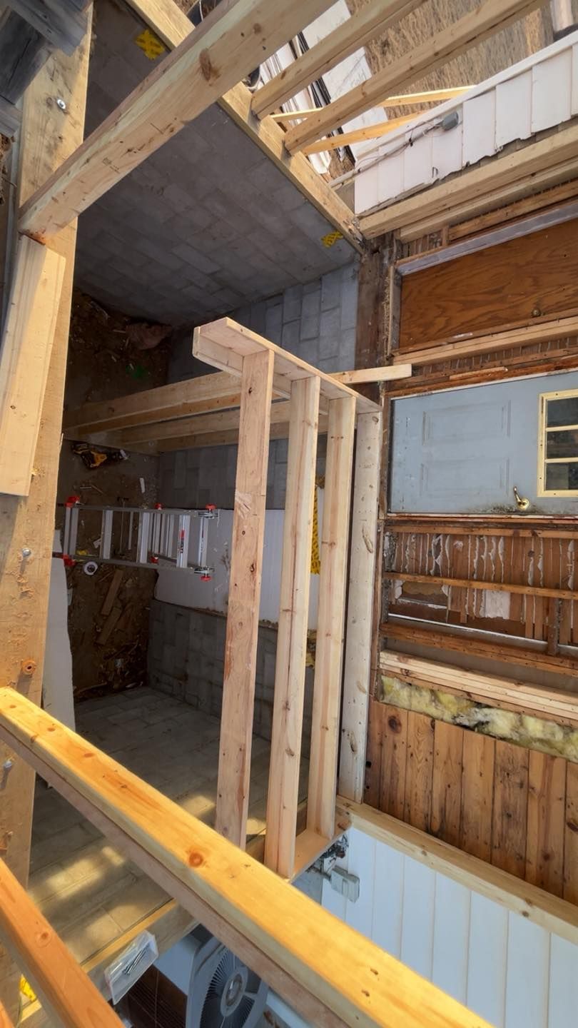 Construction view of a wooden framed partition wall being built in a room with exposed concrete and wood framing.