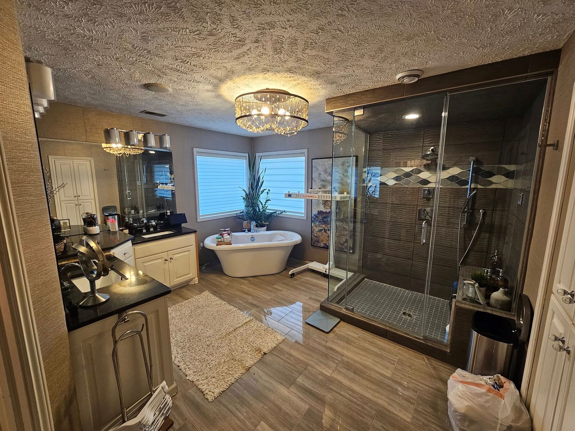 A spacious, modern bathroom featuring a walk-in tiled shower, a freestanding soaking tub, and a vanity with dual mirrors.