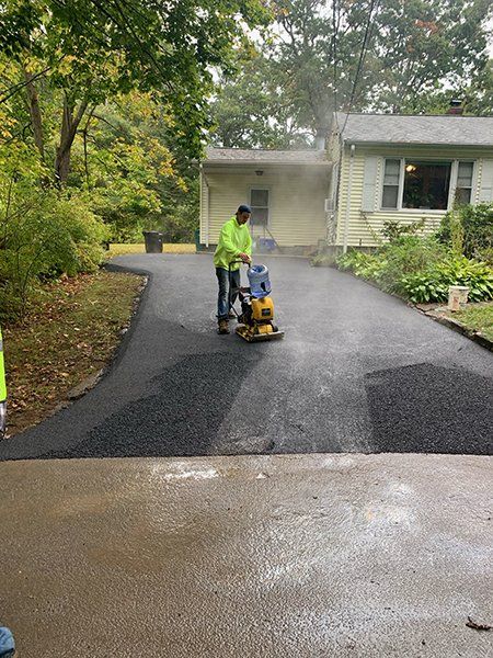 A man is paving a driveway in front of a house.
