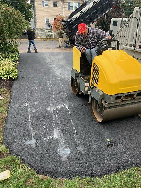 A man is riding a yellow roller on a driveway.