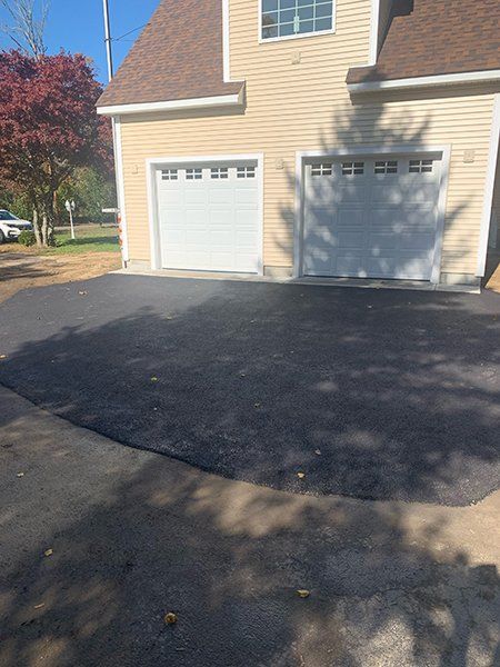 A house with two garage doors and a driveway in front of it.