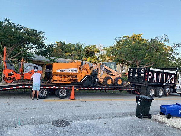 A man is standing next to a truck that says paving on it.