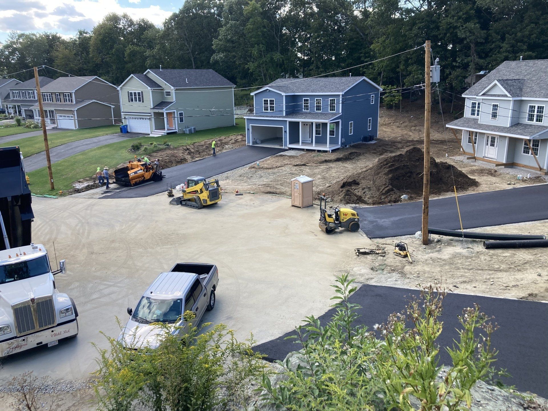 A truck is driving down a road next to a house under construction.