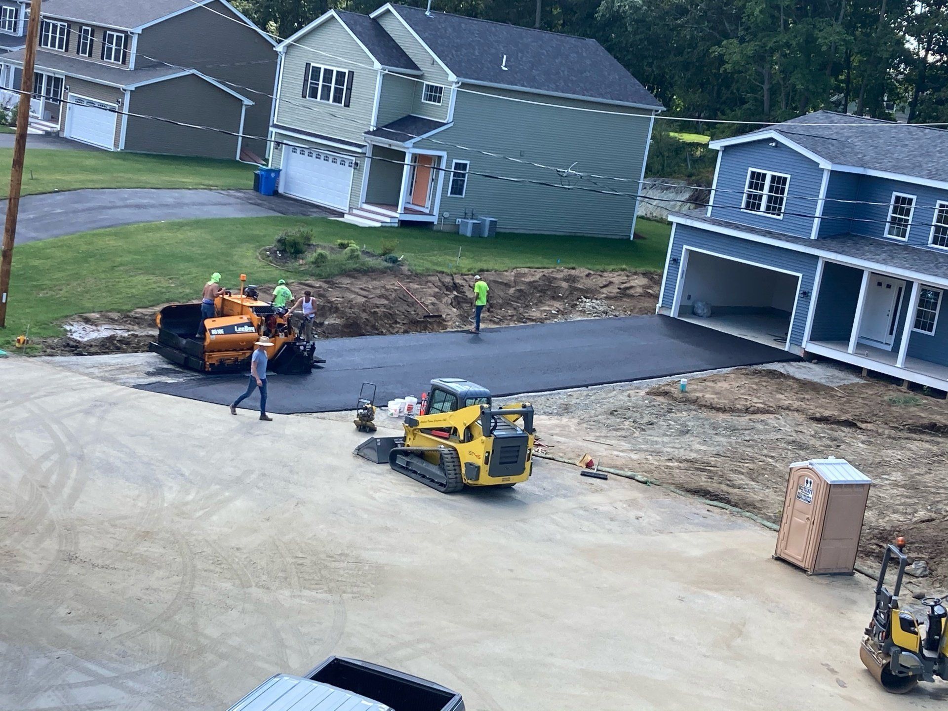 A group of construction workers are working on a road in front of a row of houses.