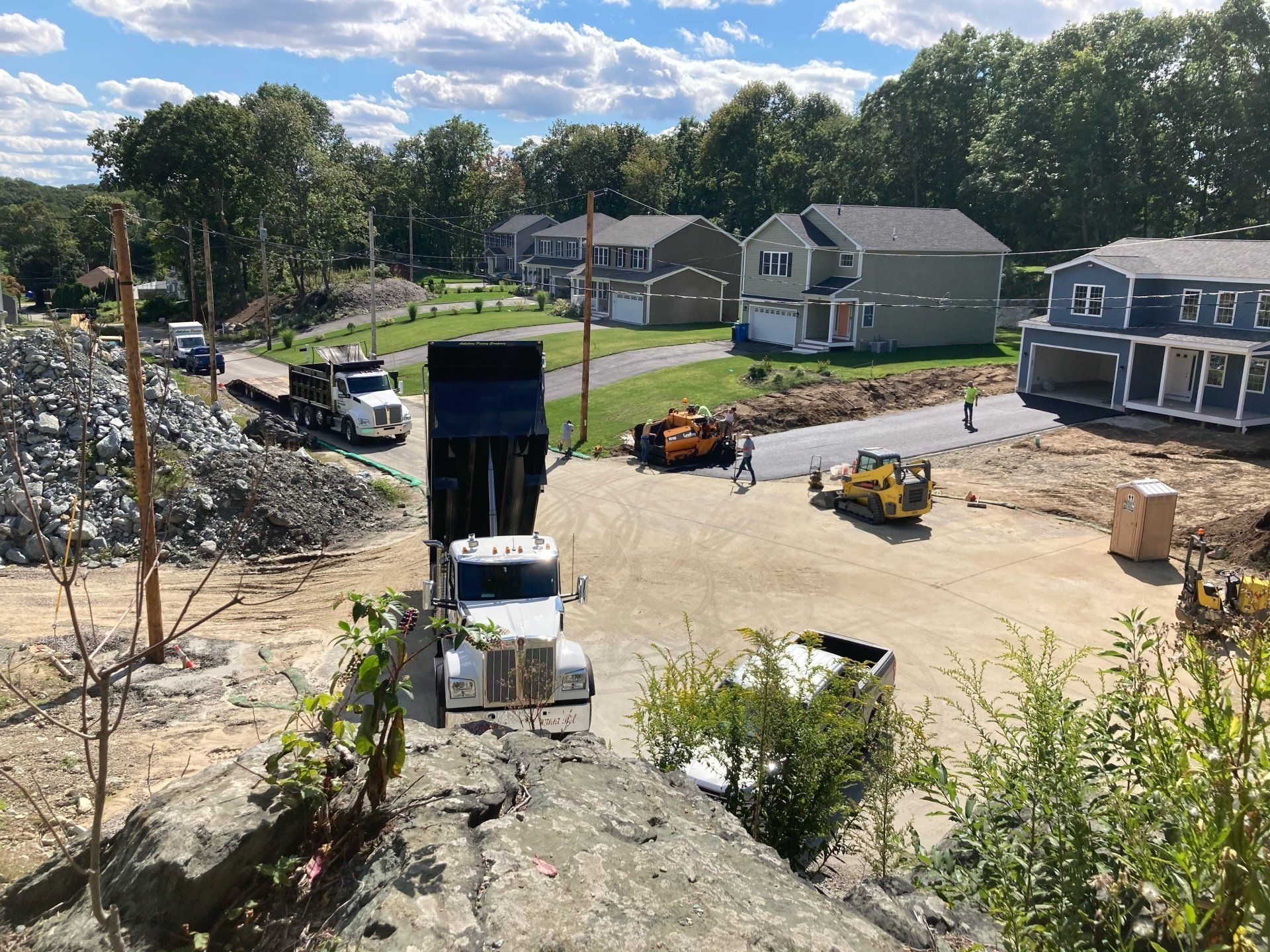 A dump truck is driving down a dirt road next to a construction site.