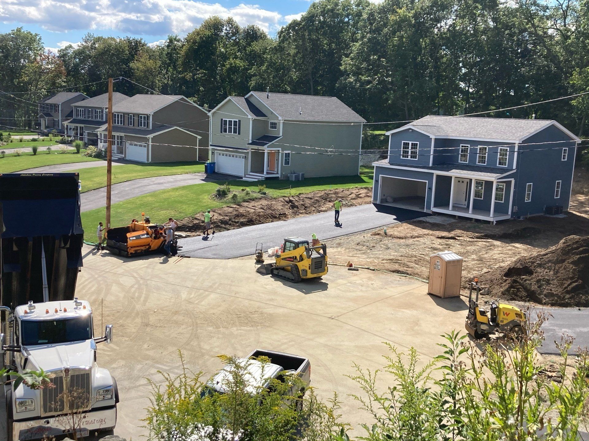 A dump truck is driving down a dirt road next to a construction site.