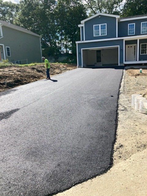 A man is standing on a driveway in front of a blue house