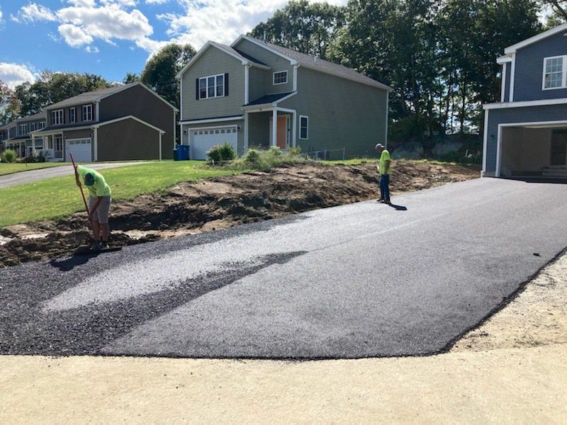 A man is working on a driveway in front of a house.
