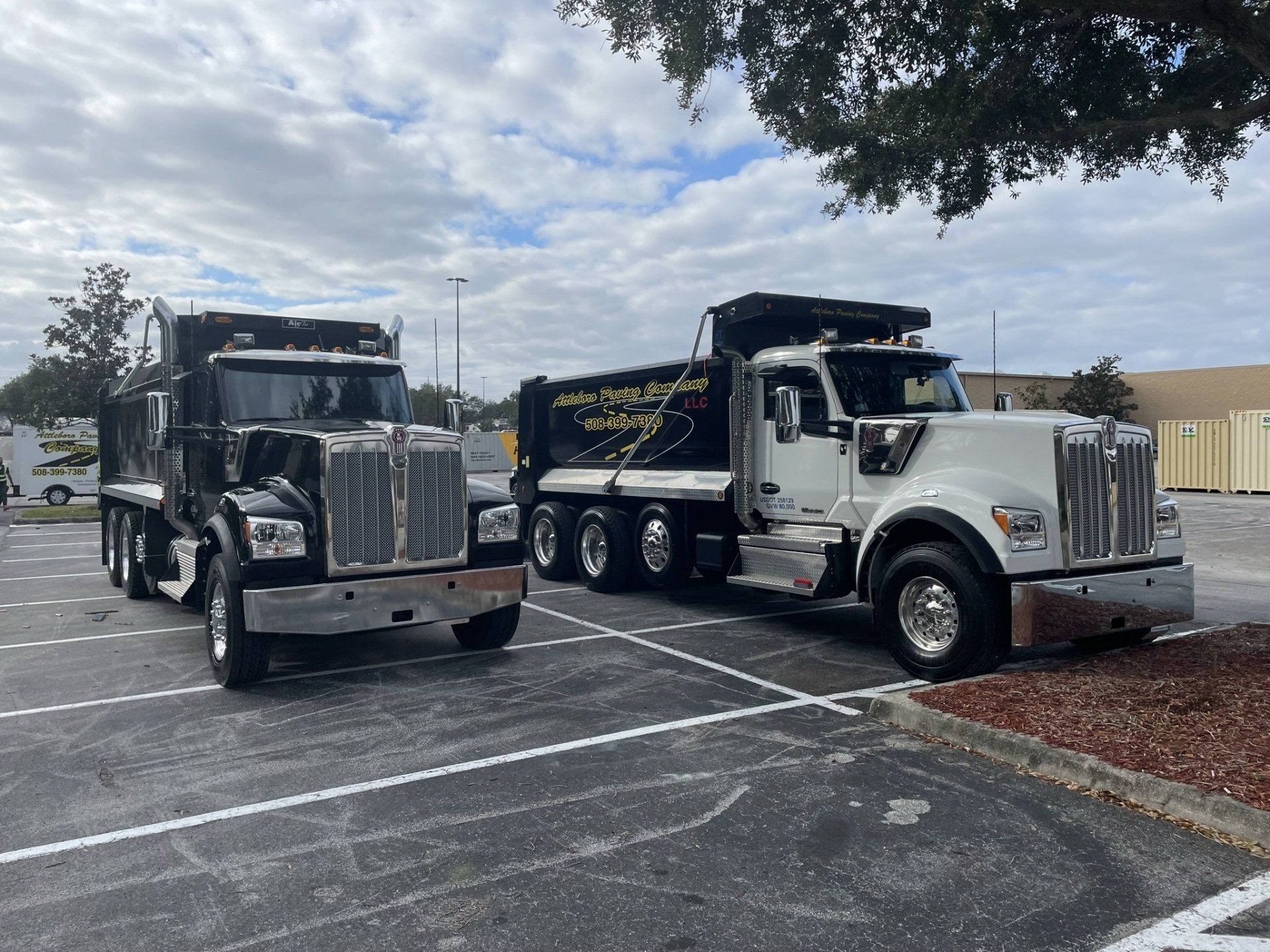 Two dump trucks are parked next to each other in a parking lot.