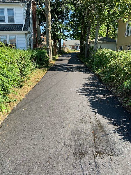 A road with trees on both sides and a house in the background