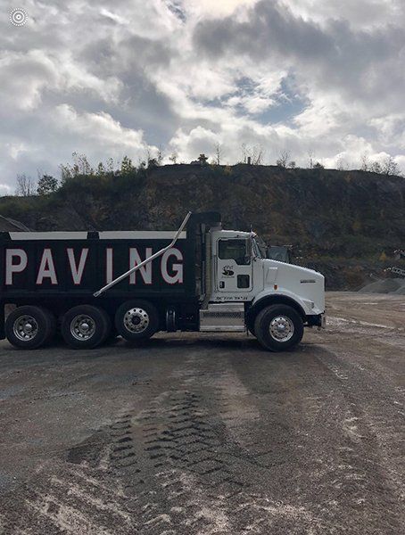 A dump truck is parked in a dirt field.