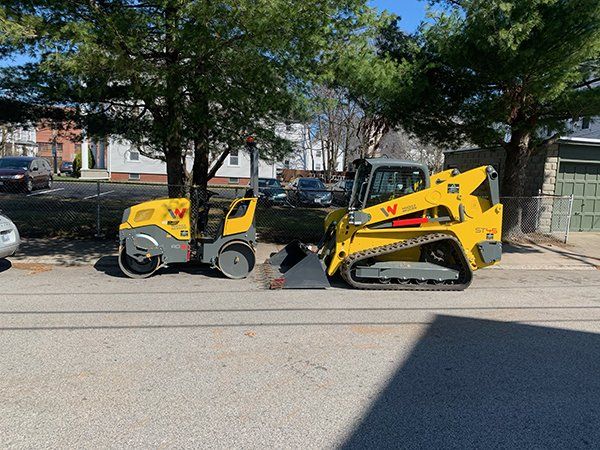 A roller and a bulldozer are parked on the side of the road.