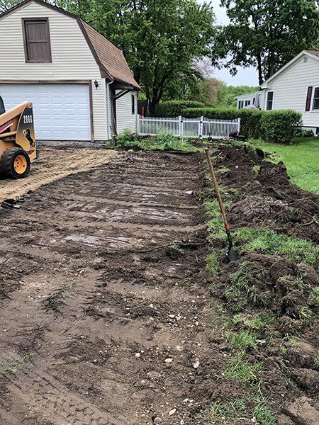 A bulldozer is moving dirt in a driveway in front of a house.