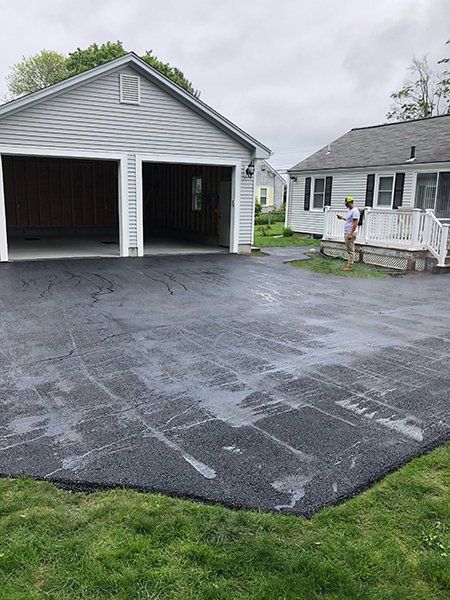 A man is standing in a driveway in front of a house.