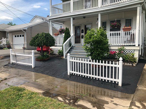 A white picket fence is in front of a house.