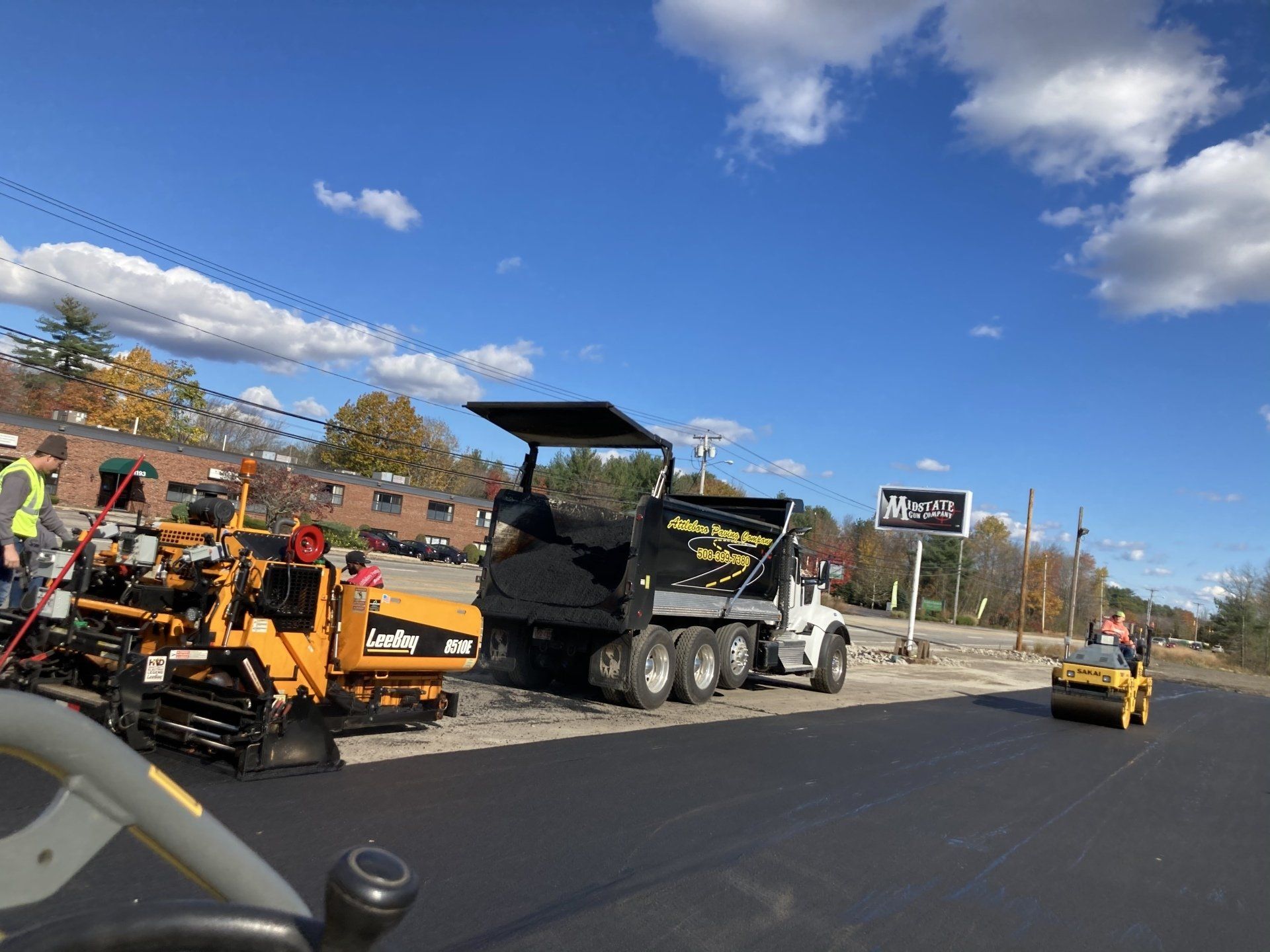 A truck is being loaded with asphalt on a road.
