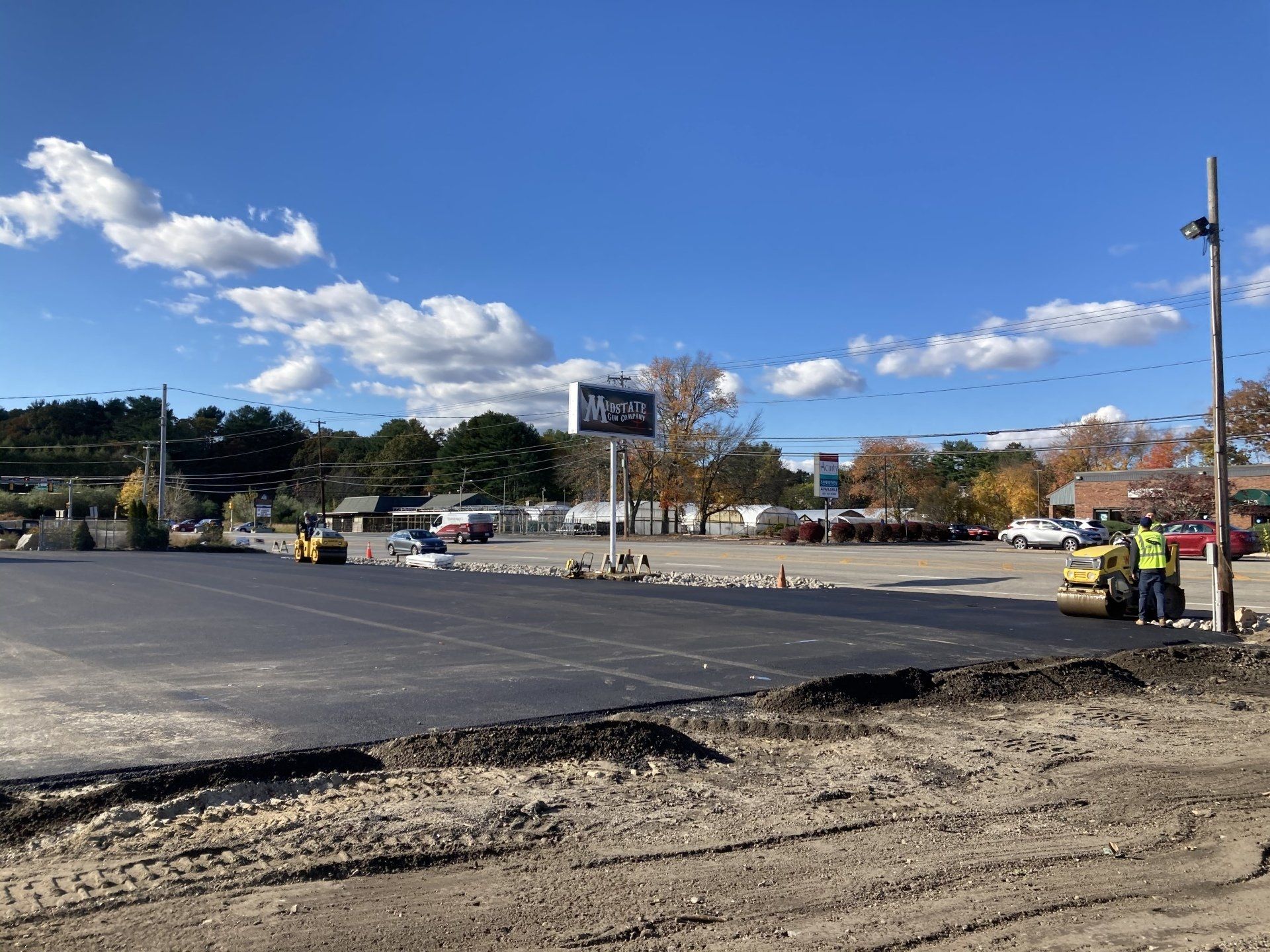 A parking lot is being paved on a sunny day.